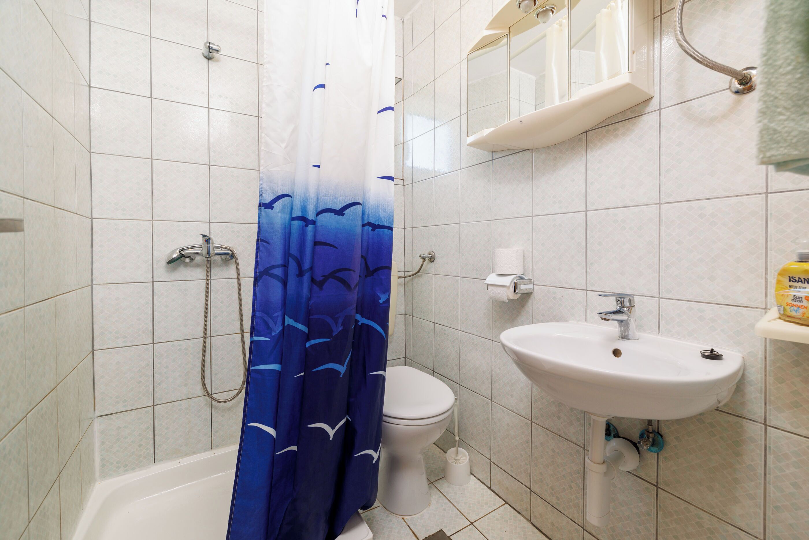 A bathroom with a shower, toilet, and sink.