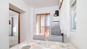 Una habitación de hotel moderna con una cama grande, una mesita, un refrigerador y una ventana con cortinas.