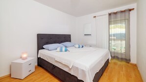 Un dormitorio con cama, mesita de noche y ventana con cortinas.