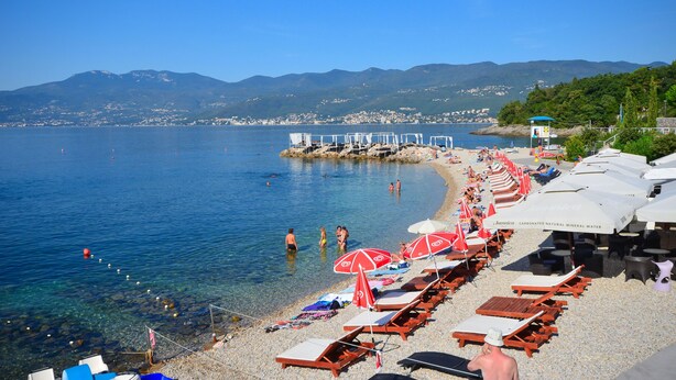 Une plage avec une eau cristalline, des parasols et des chaises longues.