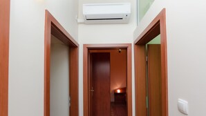 Un couloir étroit avec des portes en bois et un climatiseur fixé au plafond.