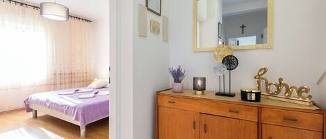 A bedroom with a bed, a wooden dresser, a mirror, and a window with curtains.
