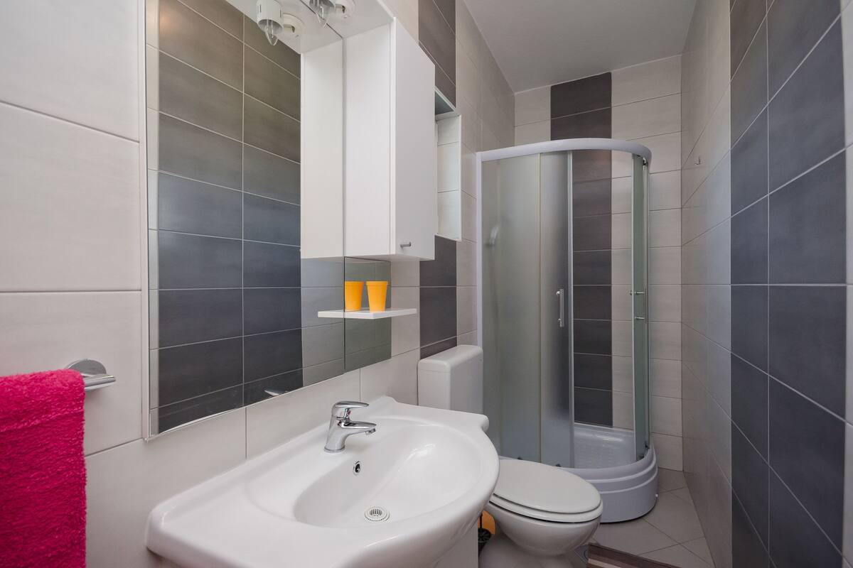Une salle de bain moderne avec un lavabo blanc, des toilettes et une douche à parois de verre.