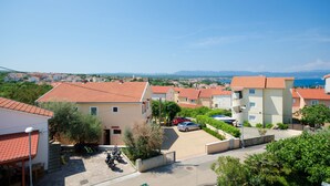 Un quartier résidentiel avec des bâtiments aux toits de tuiles rouges, un ciel d’un bleu éclatant et une vue lointaine sur la mer.