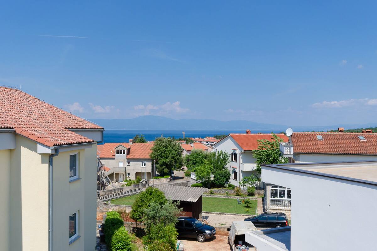 Ein Wohngebiet mit Häusern, blauem Himmel und einem fernen Blick auf das Meer.