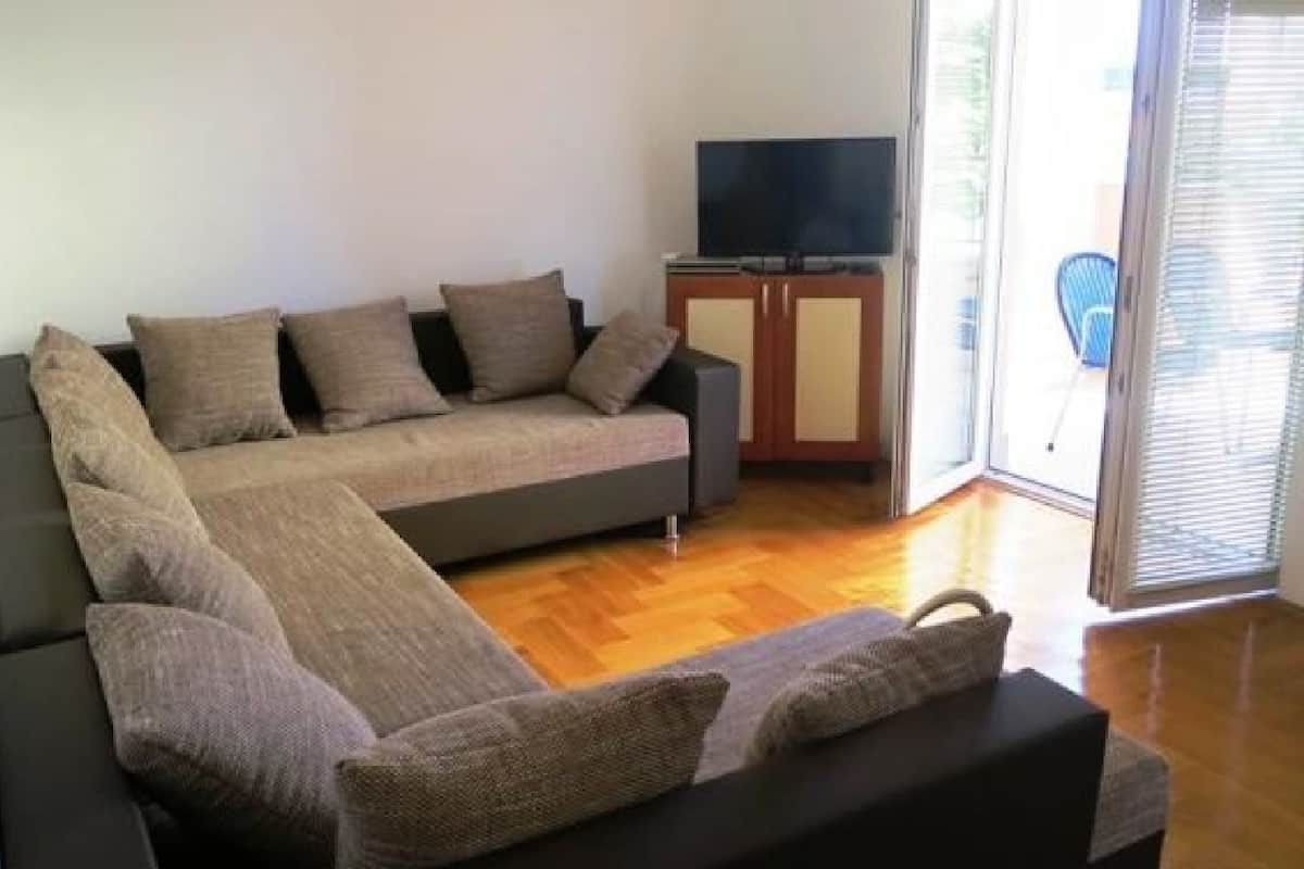 Ein modernes Wohnzimmer mit einer Couch, einem Fernseher auf einem Schrank und einer Schiebetür aus Glas.