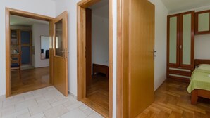 Une chambre avec un plancher en bois, un lit, une armoire et un miroir.