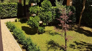 Un immeuble résidentiel doté d’un jardin, d’une pergola et d’un chemin piétonnier dallé.