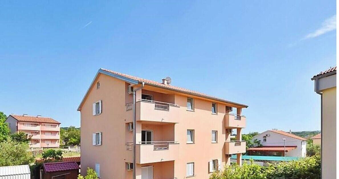 Een meerlaags woongebouw met balkons, een plat dak en een heldere lucht.