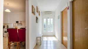 Ein Flur mit Essbereich, einem kleinen Tisch und einer Tür zu einem anderen Zimmer.