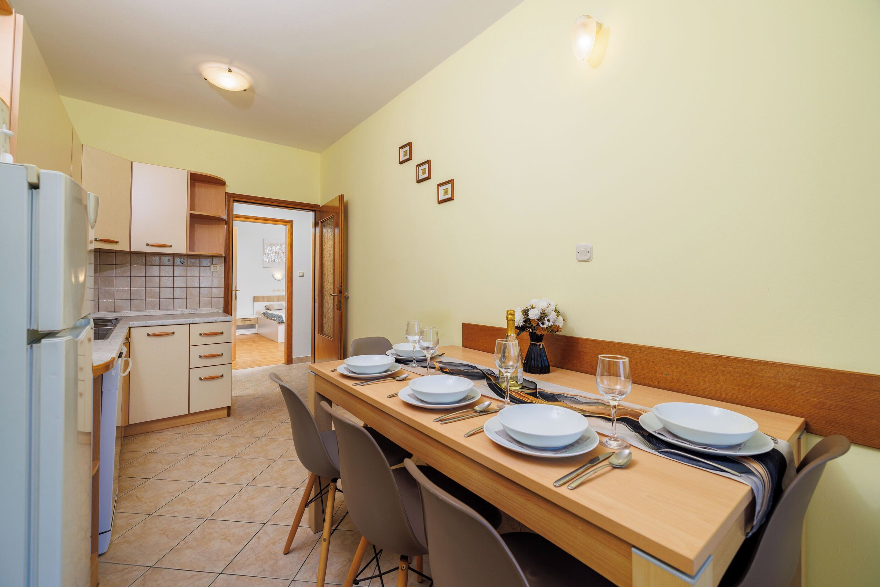 A dining area with a wooden table set for four, equipped with plates, glasses, and cutlery.