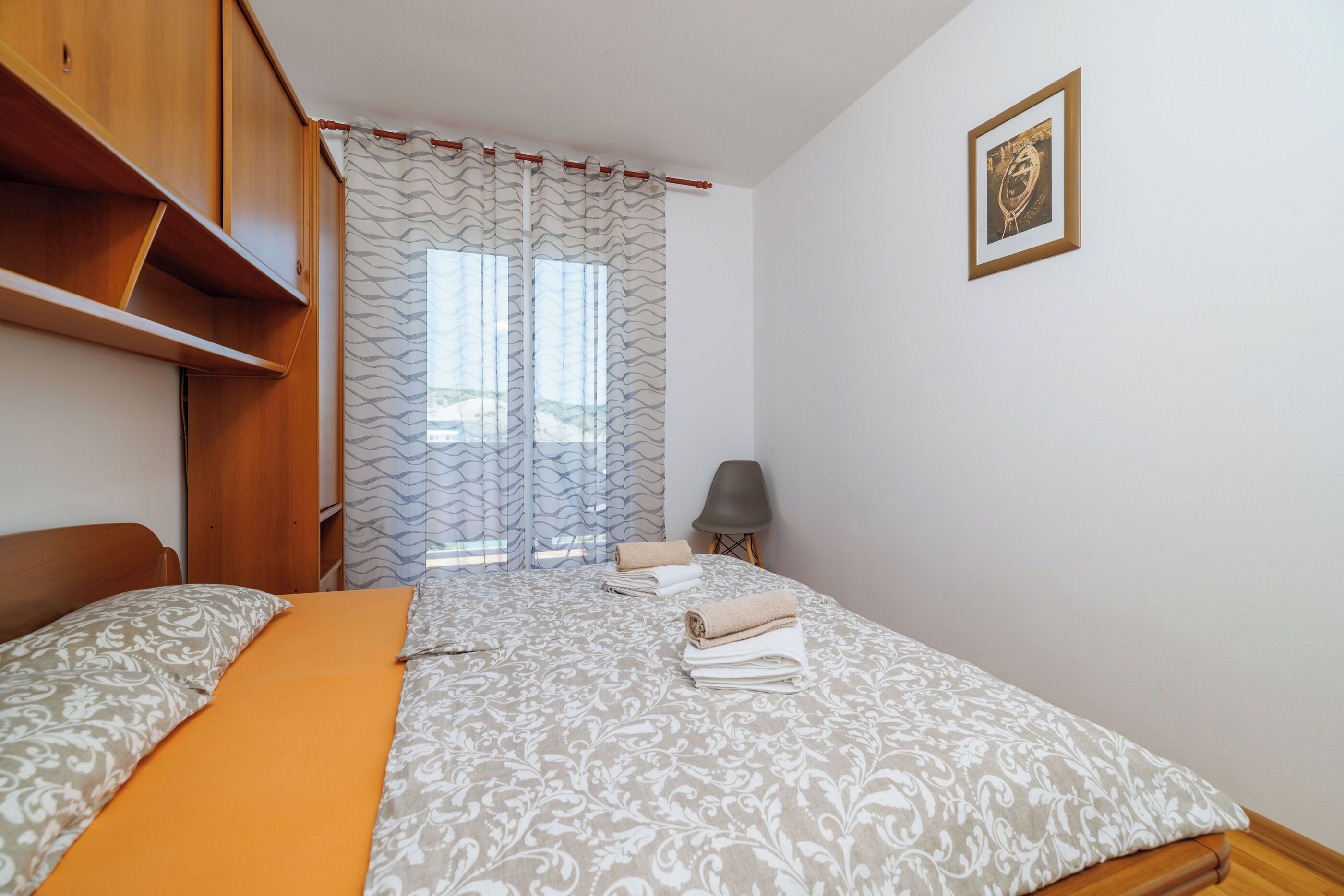 A bedroom with a bed, a chair, a lamp, and a window with curtains.