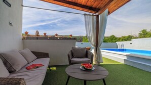 Terrassa al terrat amb una piscina, un sofà i una taula amb síndria.