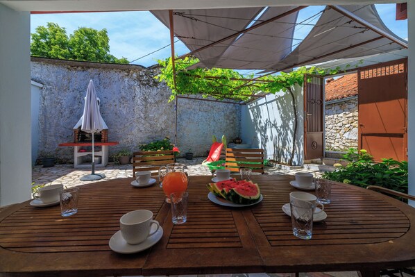 A wooden table set for breakfast with cups, a watermelon slice, and a glass pitcher.