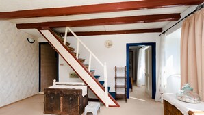 A room with a staircase, a wooden chest, a small stool, a ladder, and a window with curtains. - House Branka (Supetarska Draga)