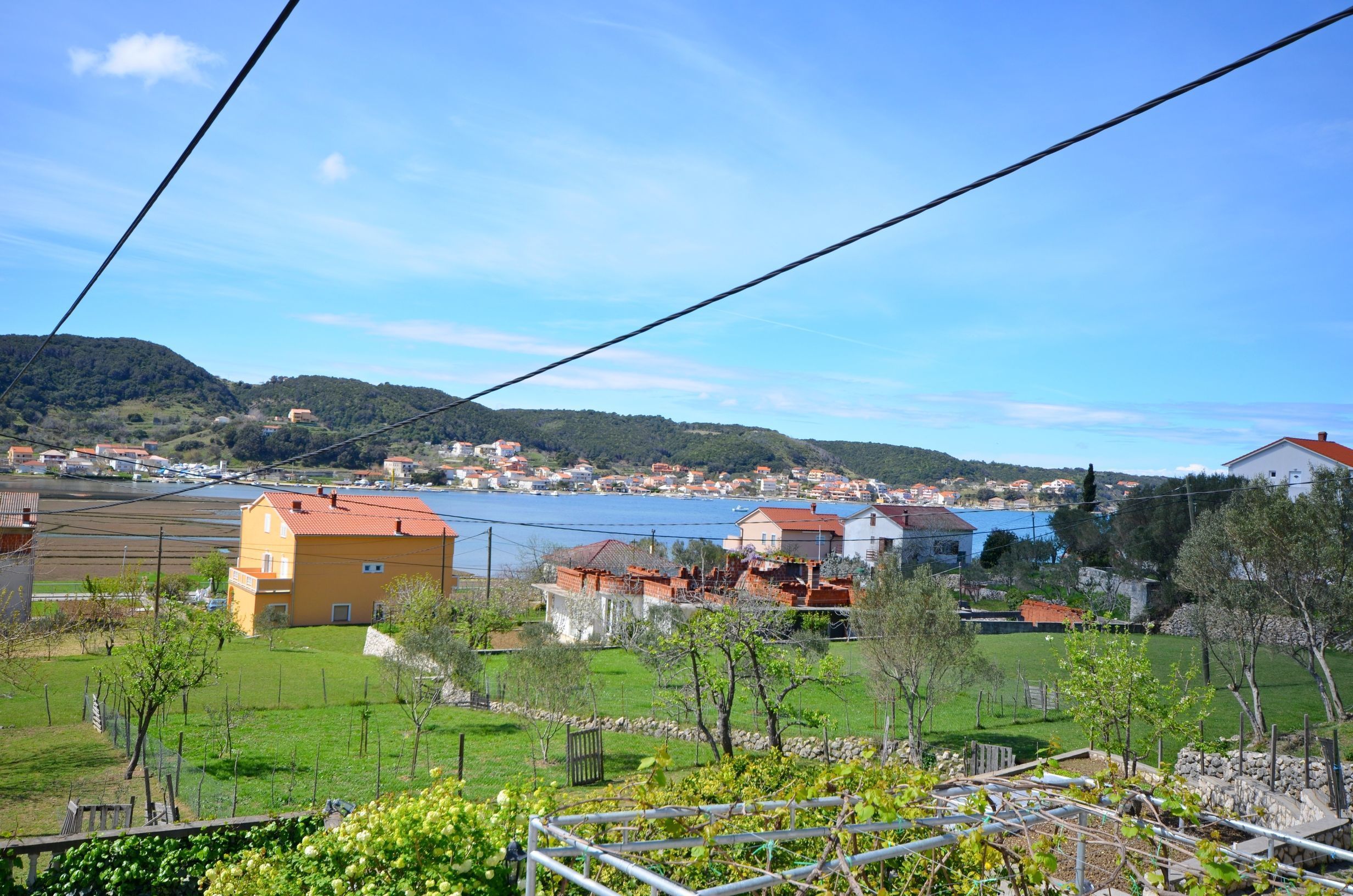 A residential area with houses, a body of water, and hills in the background.