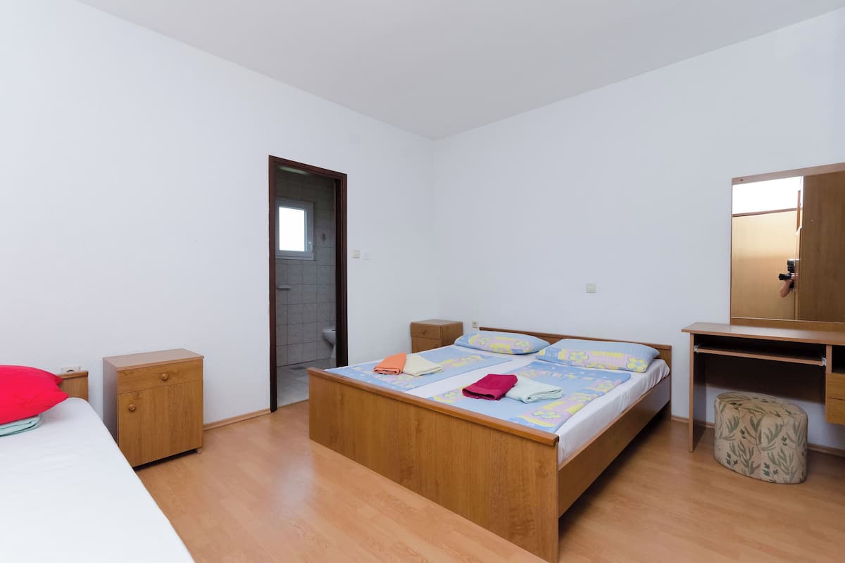 Un dormitorio con cama de madera, una mesita de noche pequeña, un armario y una puerta que da al baño.