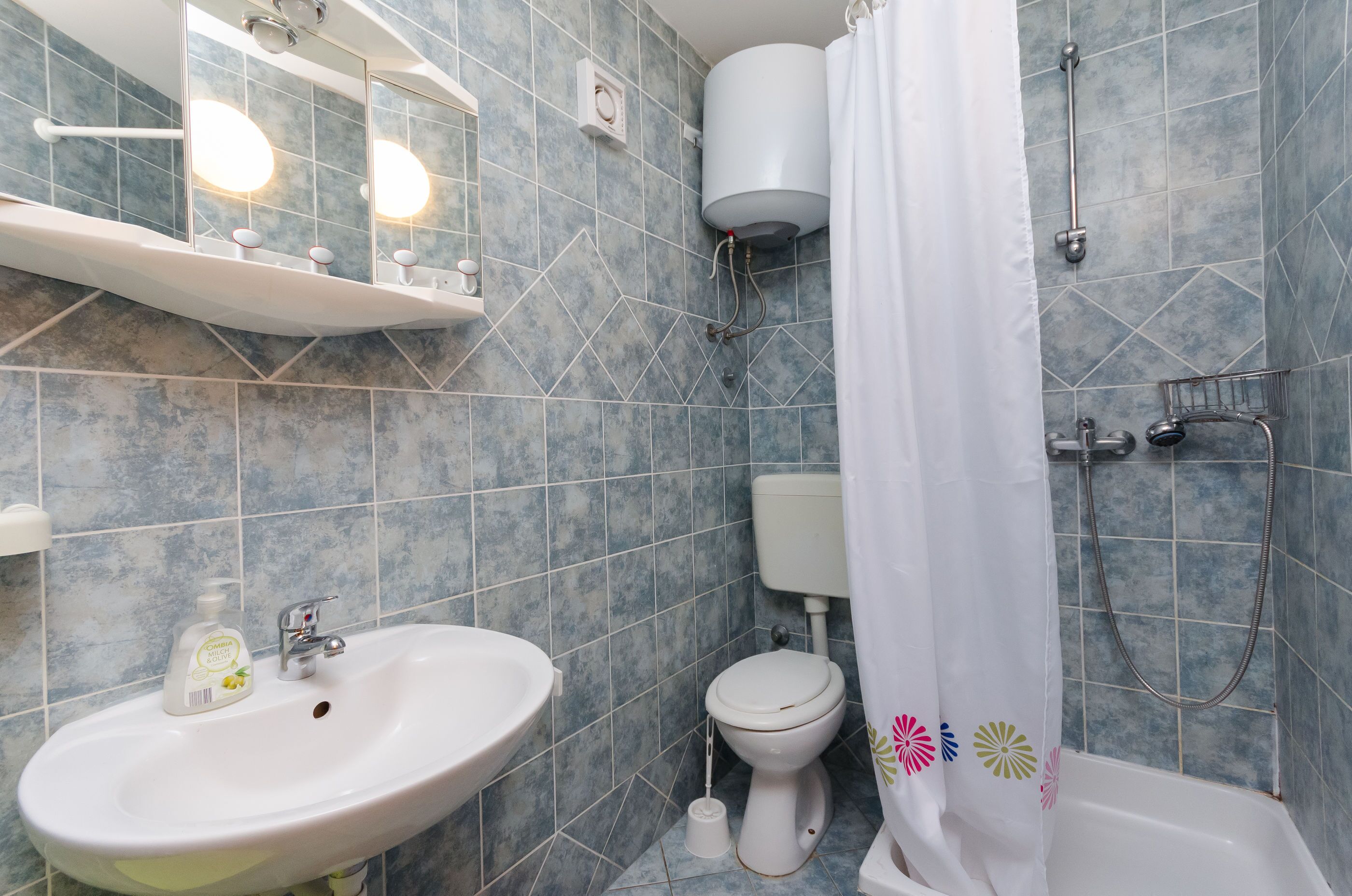 Un baño con lavamanos, inodoro y zona de ducha.