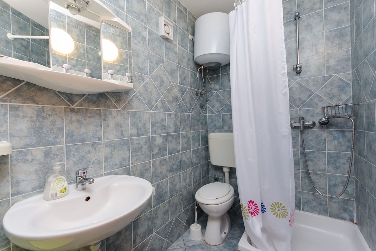 Un baño con lavamanos, inodoro y zona de ducha.