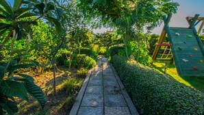 A pathway flanked by lush greenery and a climbing structure. - Apartments Boza (Lopar)