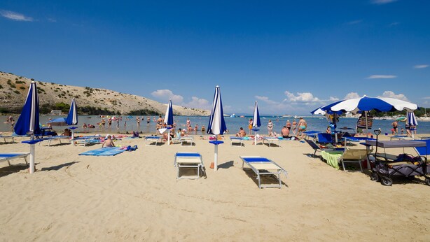A beach with sun loungers, umbrellas, and a clear view of the sea. - Apartments Helena (Lopar)