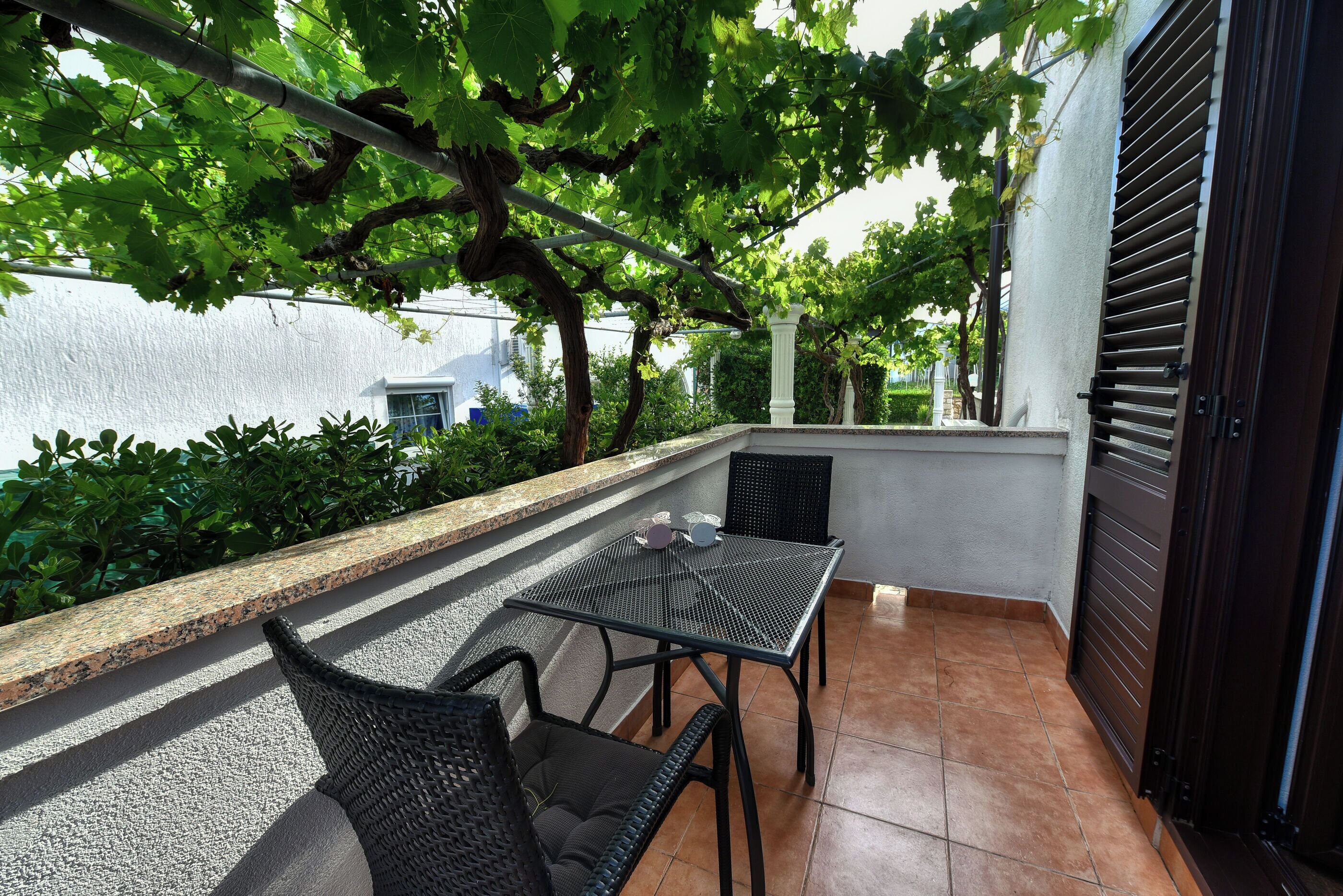 Une terrasse extérieure avec une table et des chaises, une pergola et une vue sur la ville.