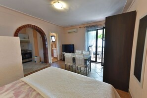 Quarto de hotel com cama, televisão, área de refeições e vista para o exterior.