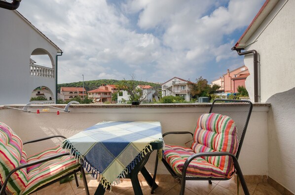 A balcony with a table and two chairs, overlooking a residential area with houses and greenery. - Apartments Helena (Lopar)