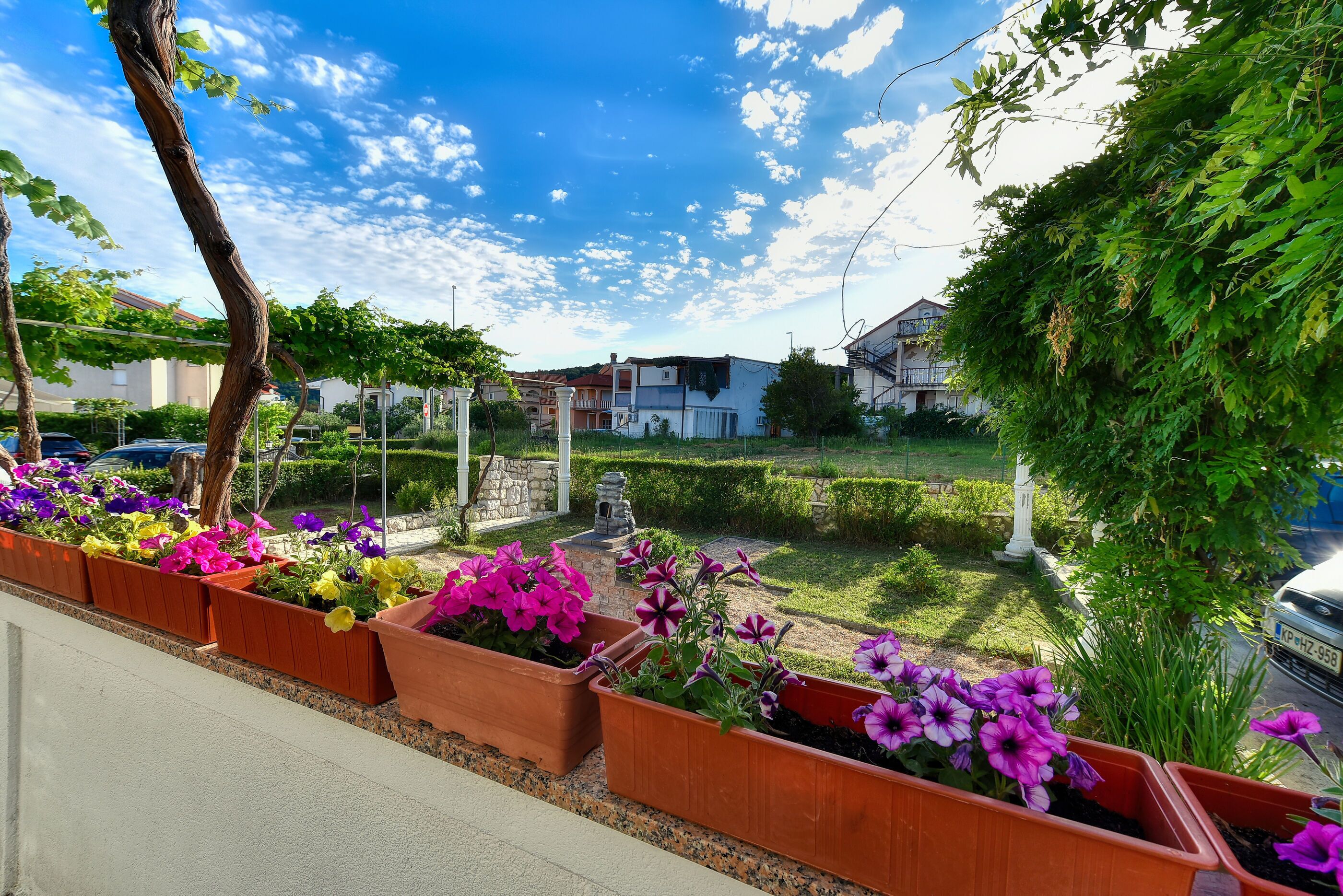 A residential area with houses, a street, and flower planters along the sidewalk.