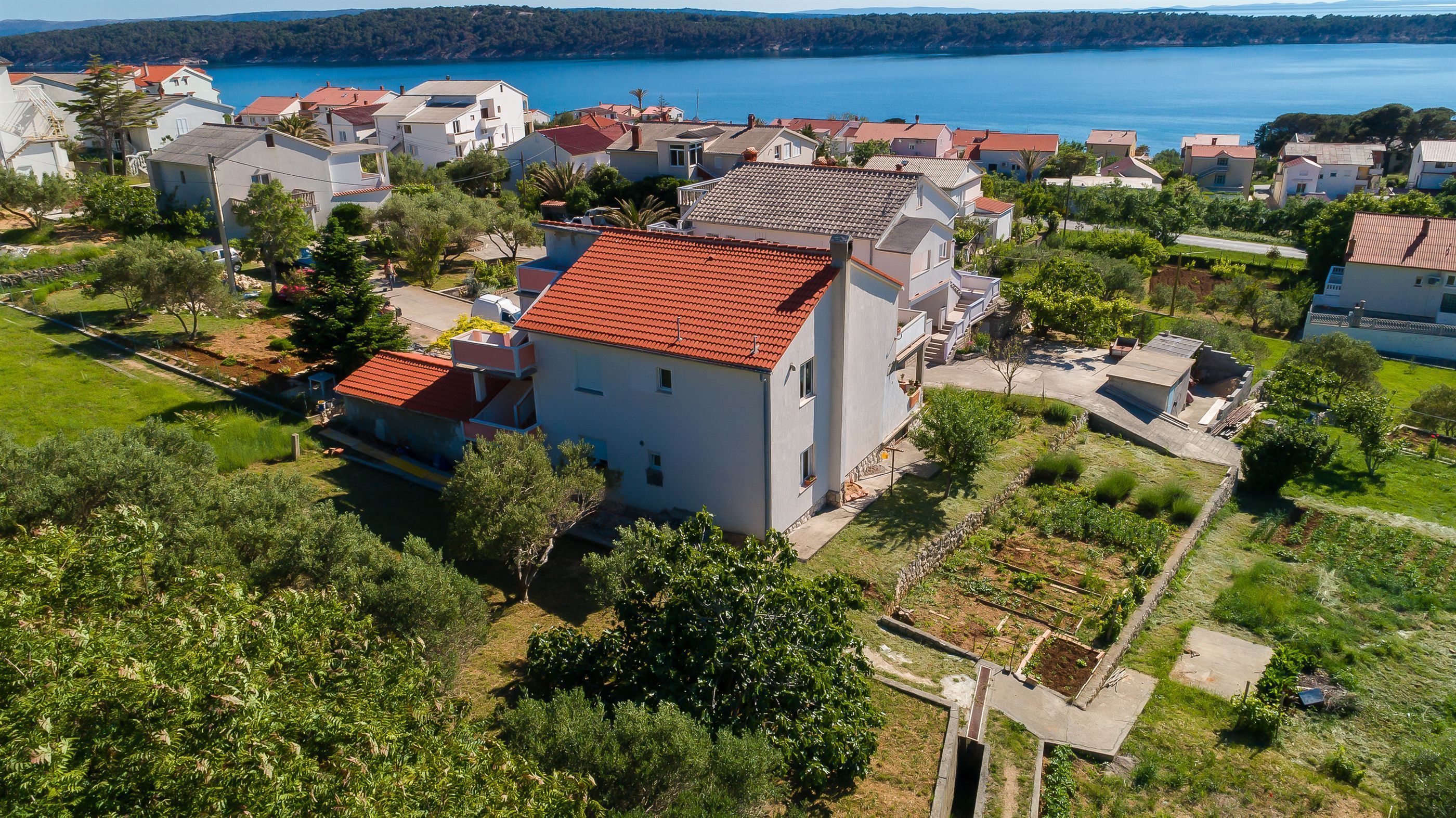 A residential area with houses, a red-roofed building, and a lake in the background.