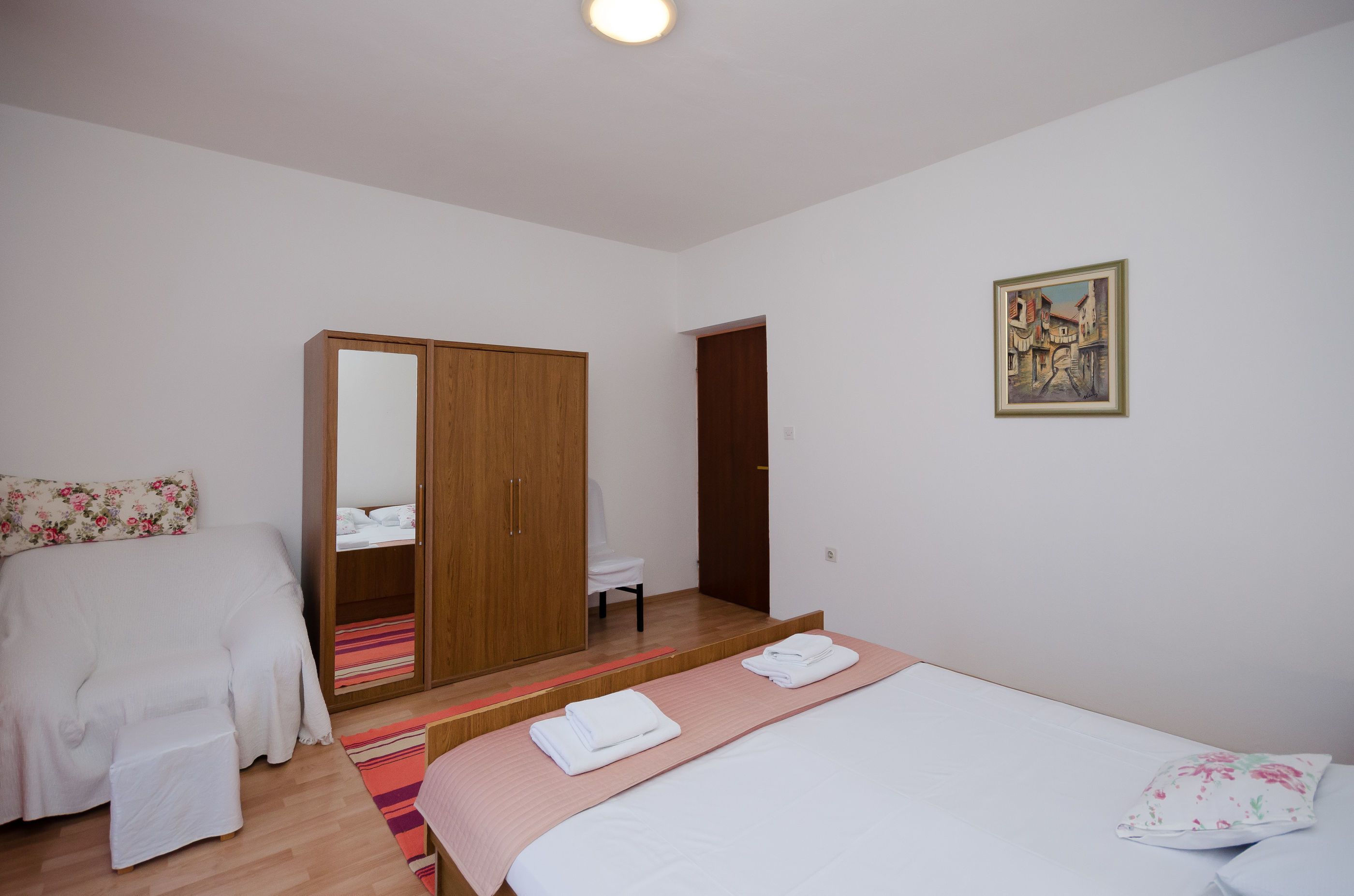 Ein Schlafzimmer mit Bett, Kleiderschrank, Stuhl und einem Gemälde an der Wand.