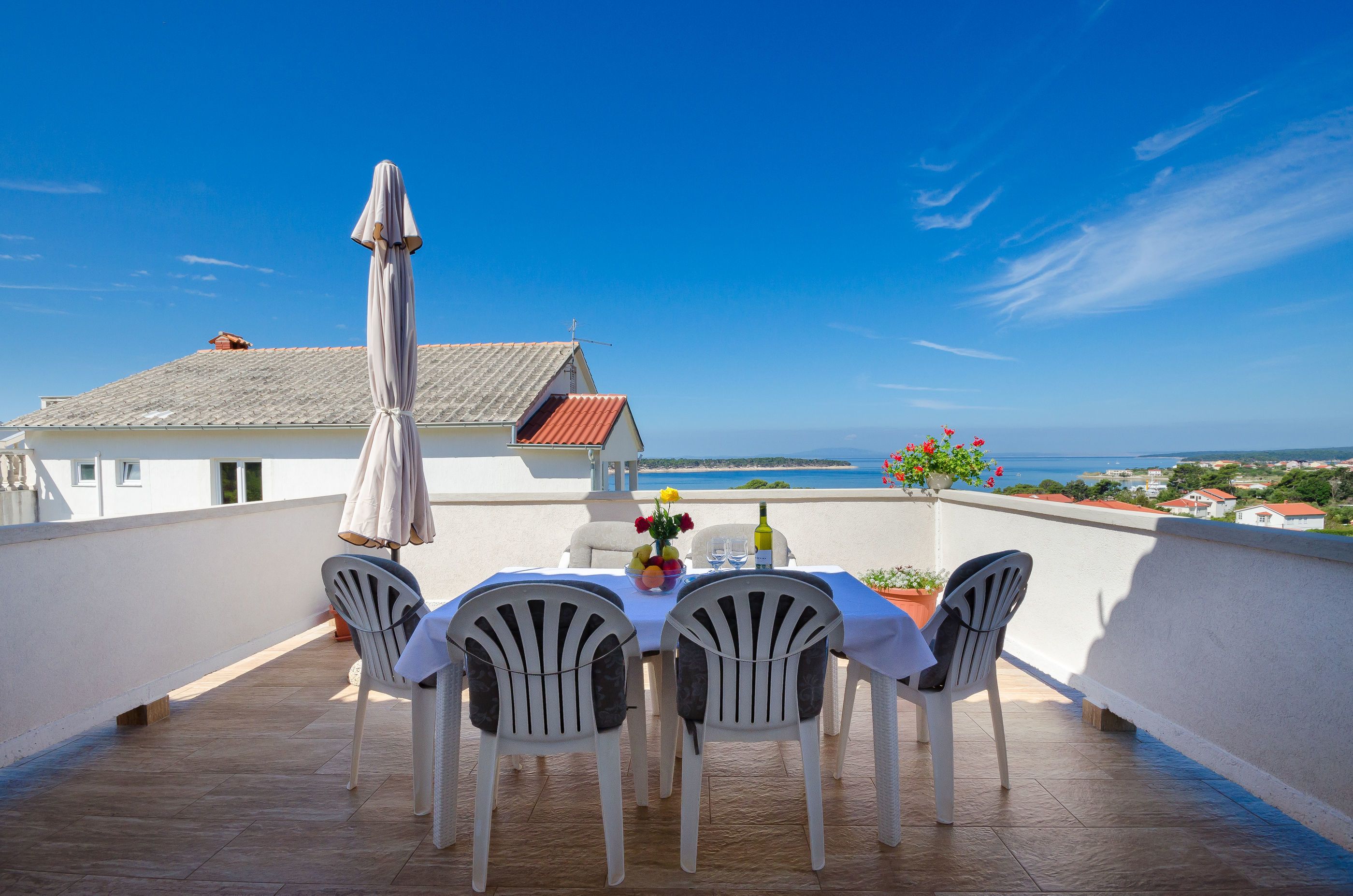 Eine Terrasse mit Tisch für vier Personen, mit Blick auf die Küste.