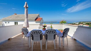 A terrace with a table set for four, overlooking a coastal view. - Apartment Milja (Banjol)
