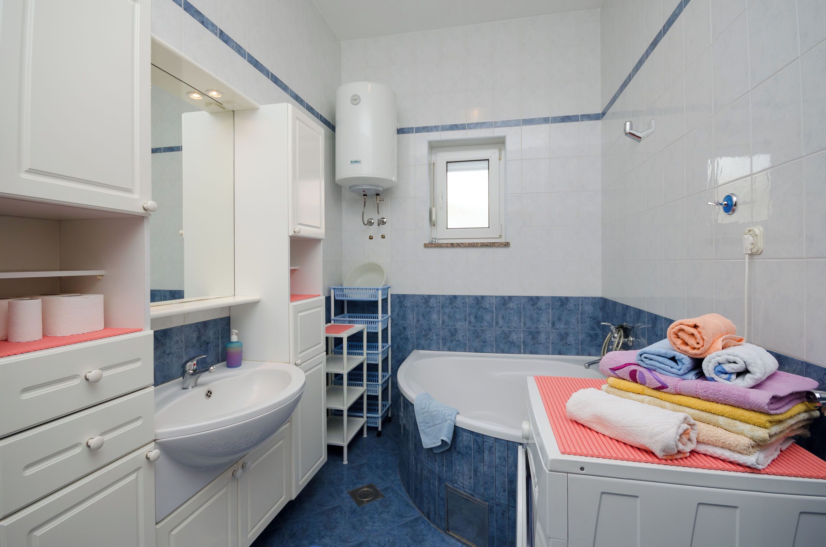 A bathroom with a sink, mirror, towel rack, and a window.