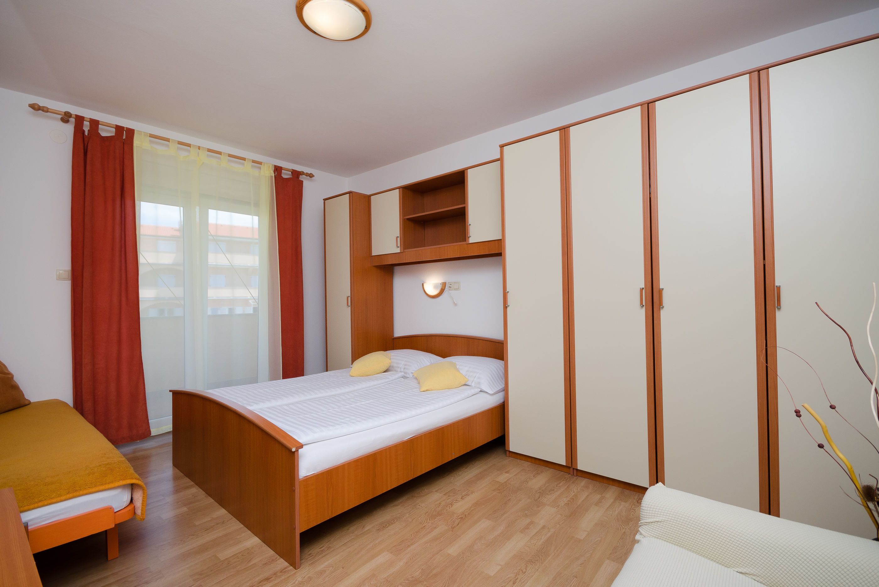 Quarto com cama de madeira, escrivaninha e guarda-roupa.