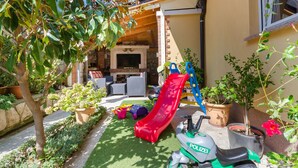 A patio with a red slide, a scooter, and potted plants. - Apartments Mirjana (Lopar)