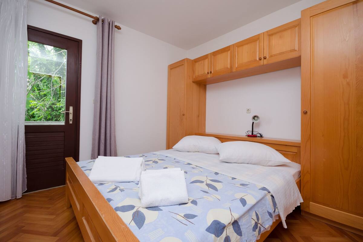 A neatly made bed with a floral bedspread, wooden headboard, and a bedside table with a lamp.
