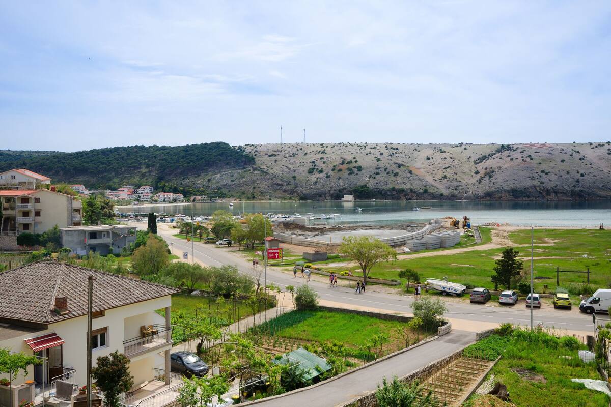 A coastal town with a road leading to a beach, houses, and a construction site.