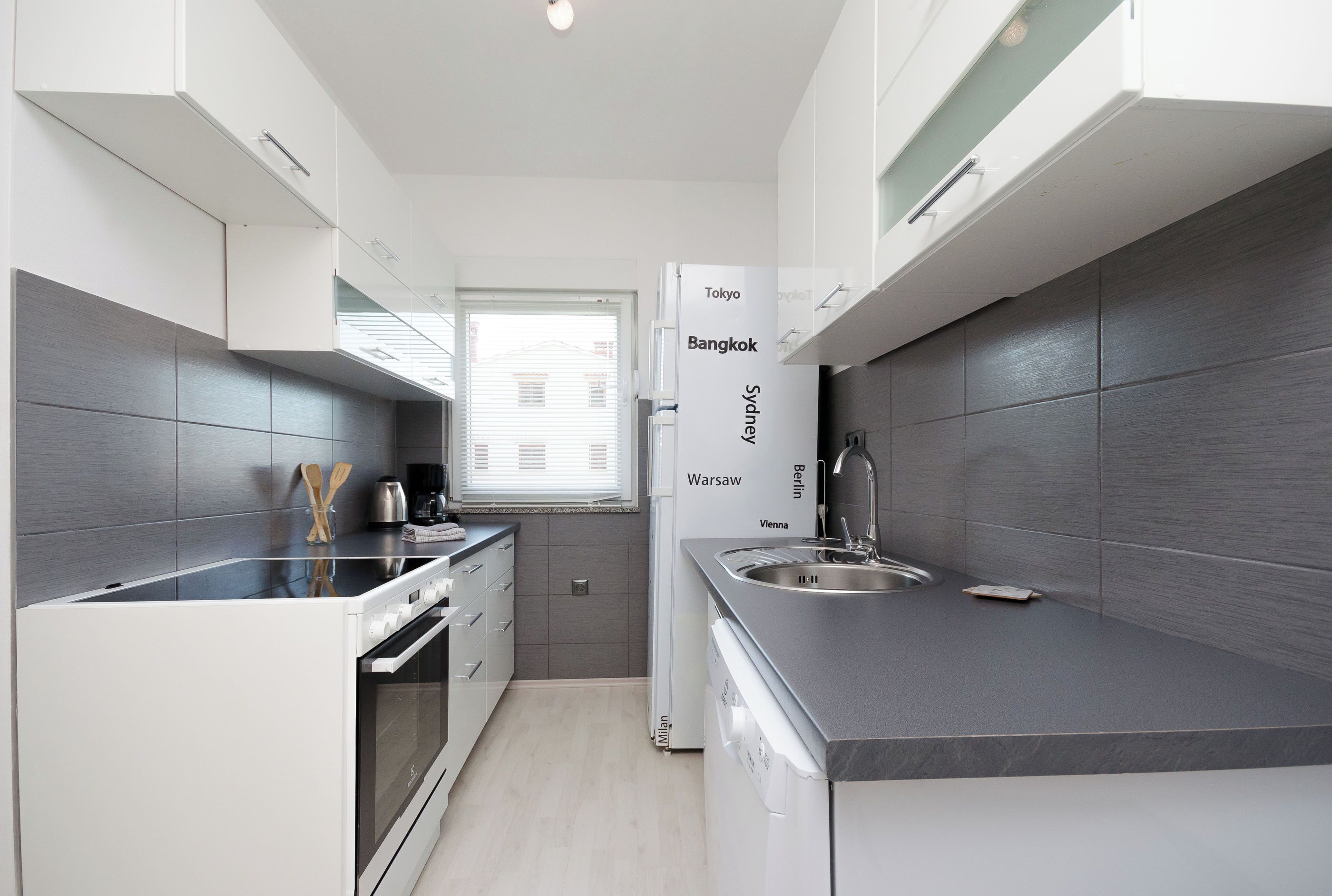 Una cocina compacta con electrodomésticos modernos, horno empotrado y fregadero.