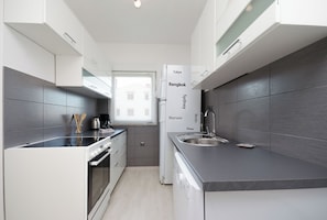A modern kitchen with white cabinets, a built-in oven, a coffee maker, and a sink.