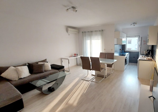 Ein modernes Wohnzimmer mit einem Glastisch, einer Couch und einem Essbereich mit Stühlen.