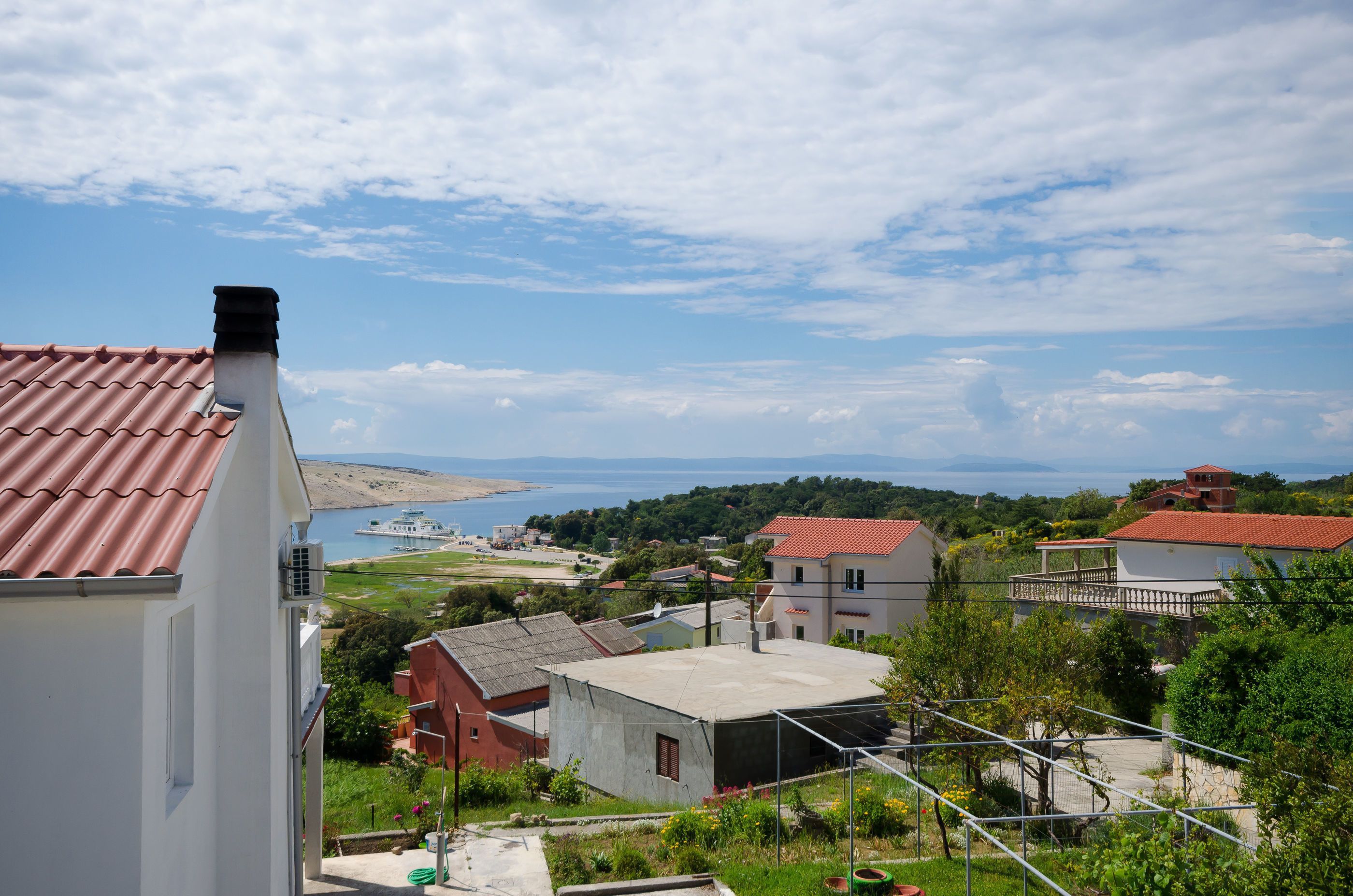 Ein Küstendorf mit terrakottafarbenen Häusern, einem klaren Himmel und Blick auf das Meer.