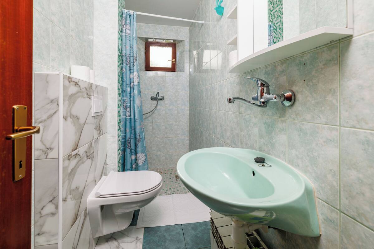 Ein Badezimmer mit Toilette, Waschbecken und Duschbereich.
