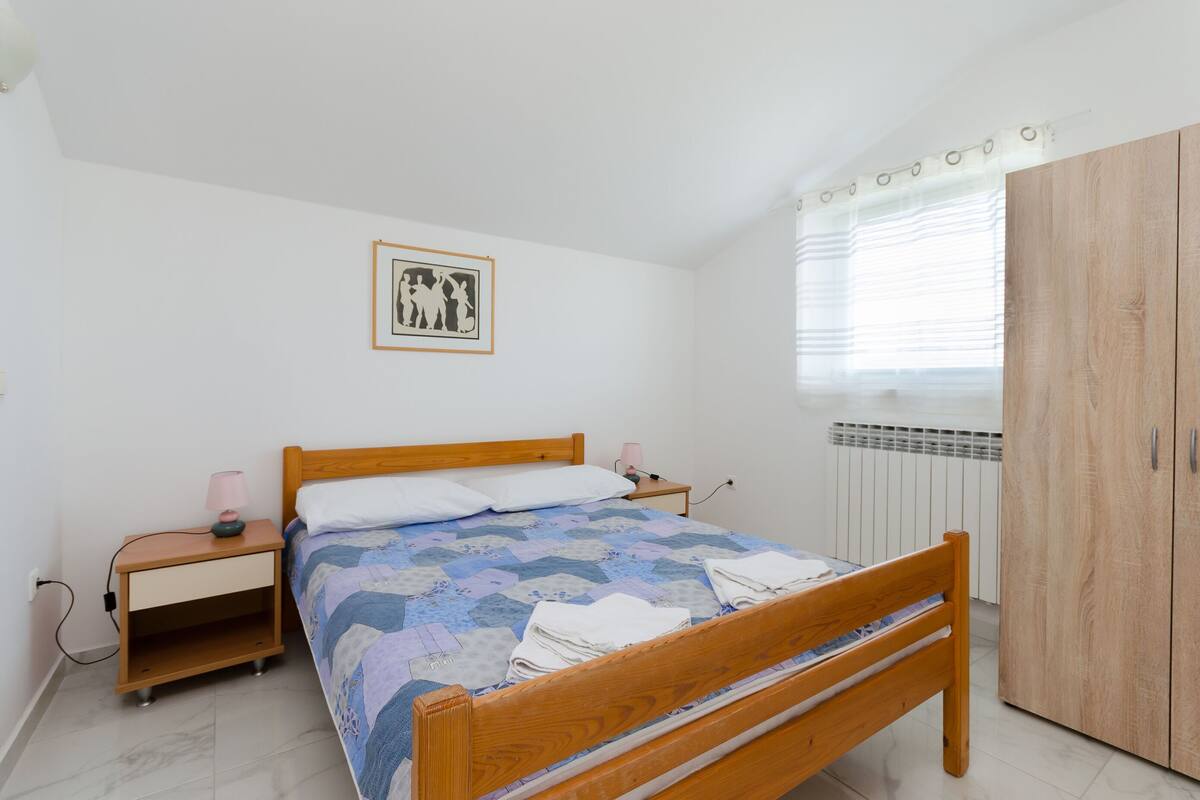 Ein Schlafzimmer mit einem hölzernen Bett, einem Nachttisch, einem Kleiderschrank und einer Heizung.