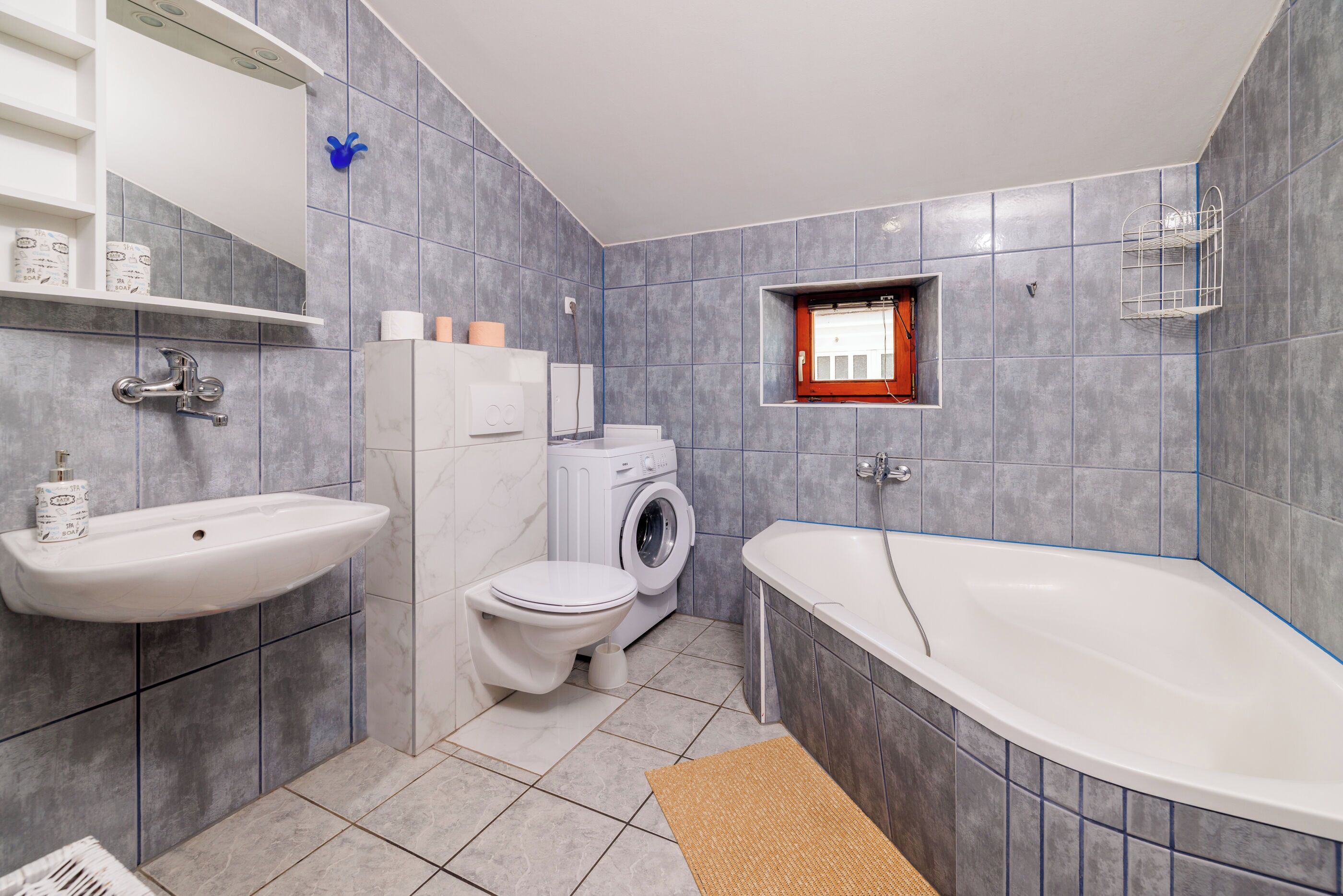 Un bagno moderno con lavandino, WC, lavatrice e vasca da bagno.