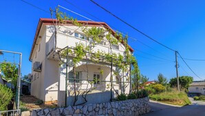 A two-story building with a stone foundation and a red roof. - Apartments Slobodanka (Lopar)