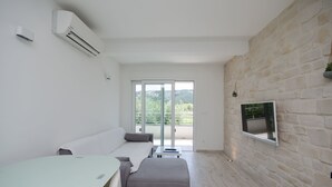 Ein modernes Wohnzimmer mit einer Couch, einem Hocker und einem Flachbildfernseher, der an einer Steinwand angebracht ist.