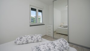 Ein Schlafzimmer mit einem Bett, einem Schminktisch, einem Fenster und einem Spiegel.