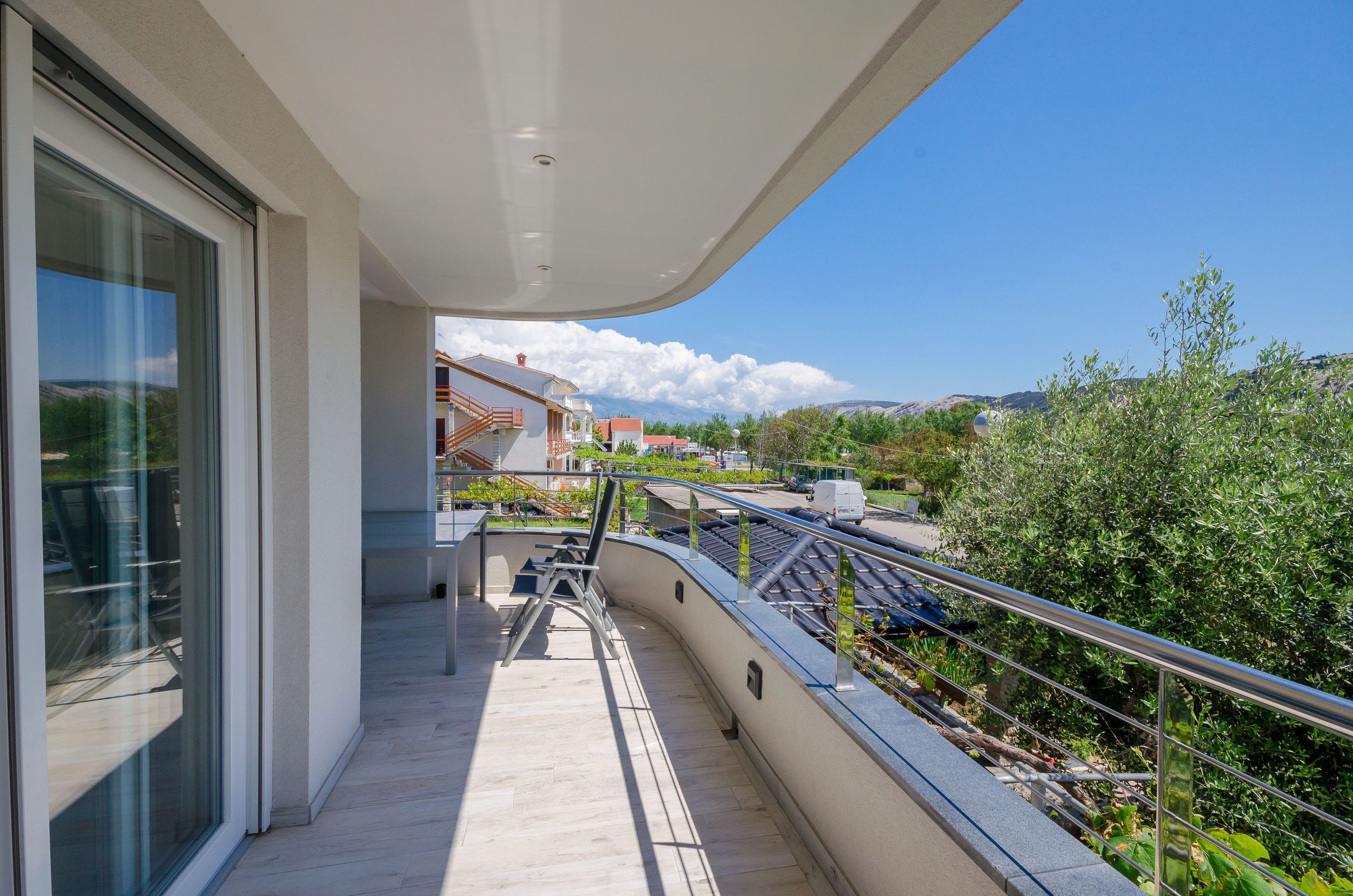 A balcony with a view of a residential area, a pathway, and a railing.