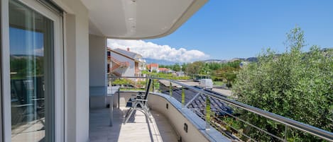 A balcony with a view of a residential area, a pathway, and a railing.